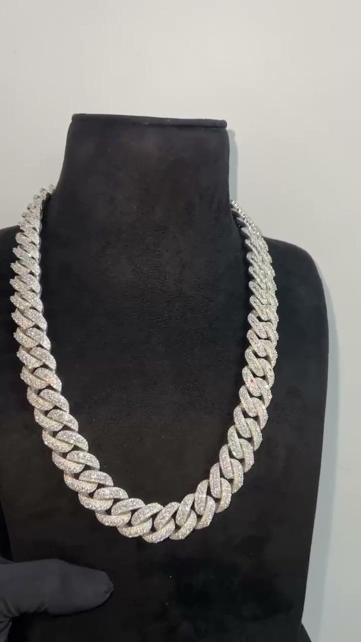 Broad stone-set Cuban-style chain displayed around a dark necklace bust.