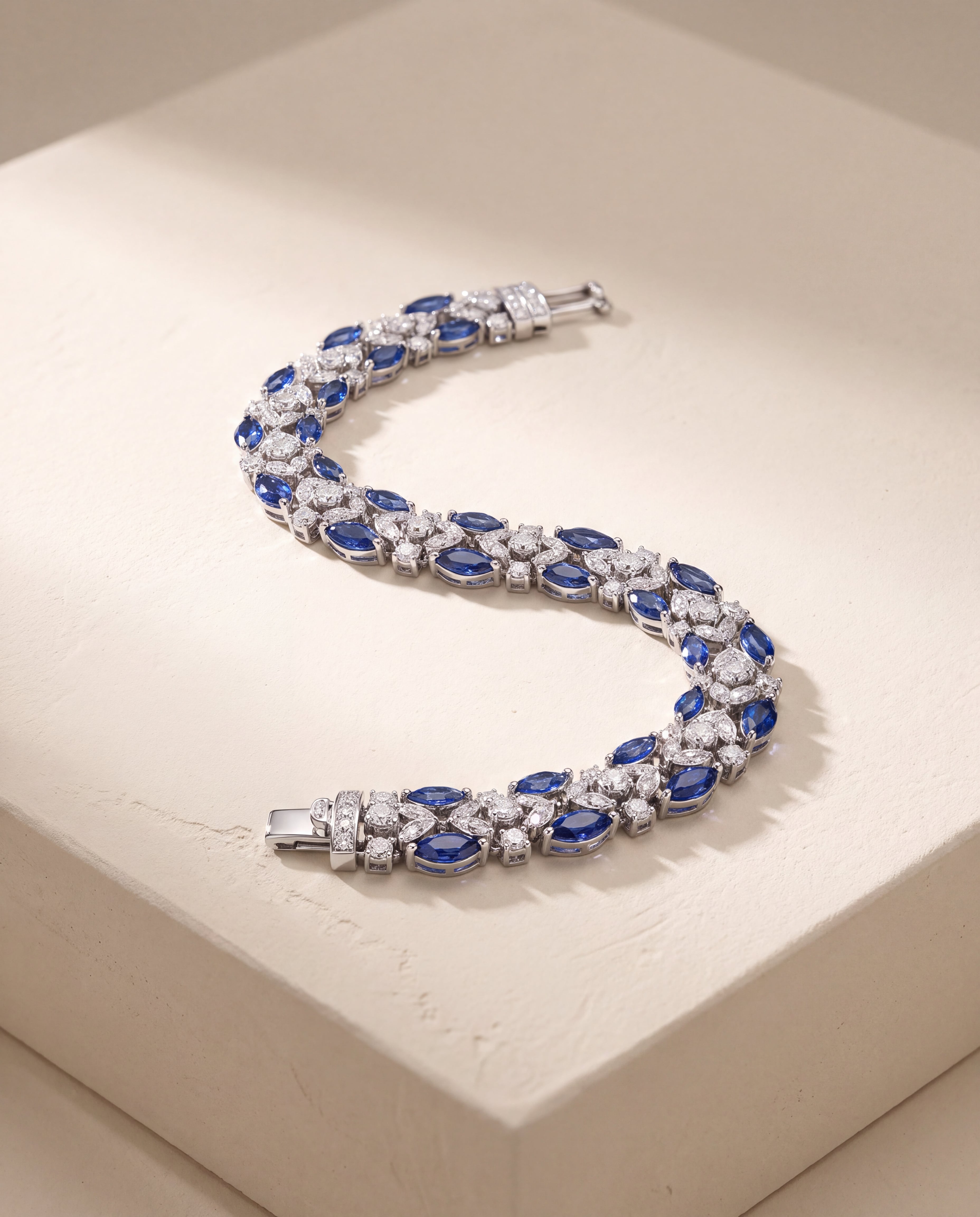 A silver-tone bracelet with blue and clear stones arranged in a curve on pale stone.
