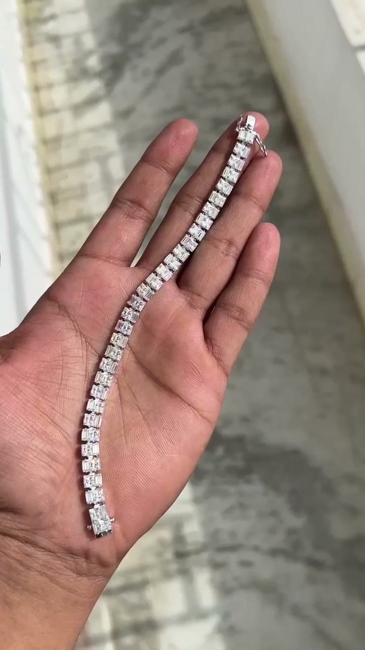 Single-row bracelet with square-faced stone settings and visible clasp hardware resting across a palm.