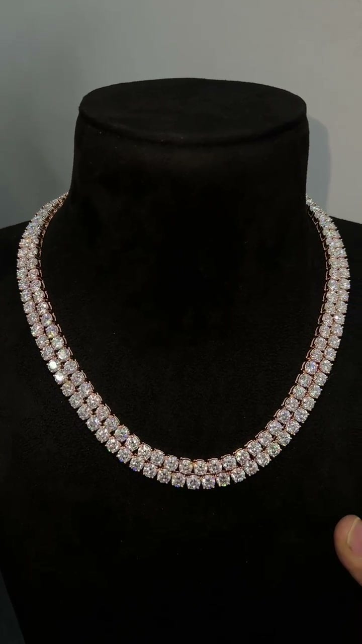 Two closely layered rows of round stone settings displayed on a dark necklace bust.
