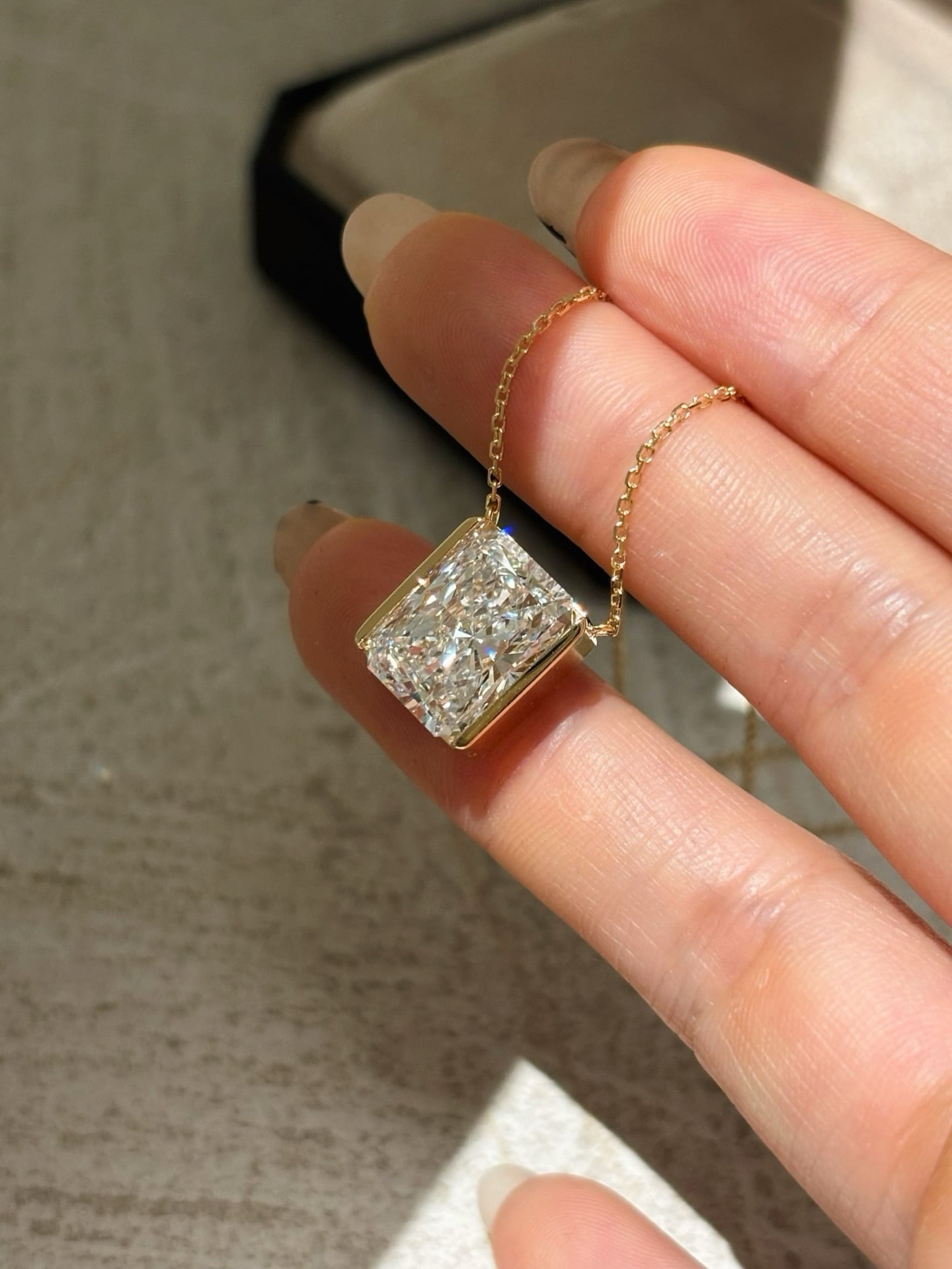 Angled close view of the same rectangular pendant showing the side rails, exposed short ends and chain attachments.